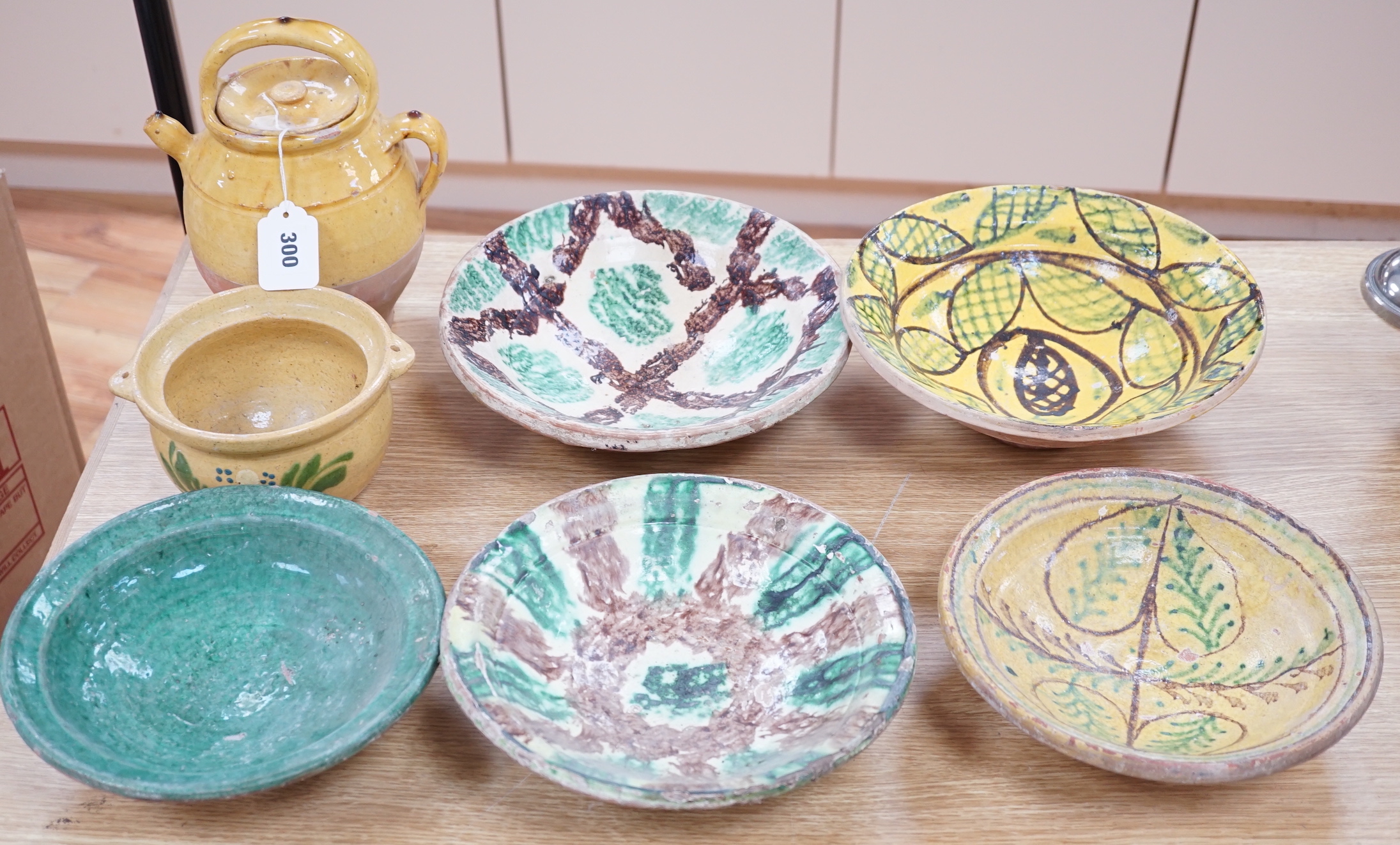 A group of Mediterranean slip decorated pottery dishes, a jar and cover and a bowl, predominantly with yellow and green grounds, the largest 26cm in diameter